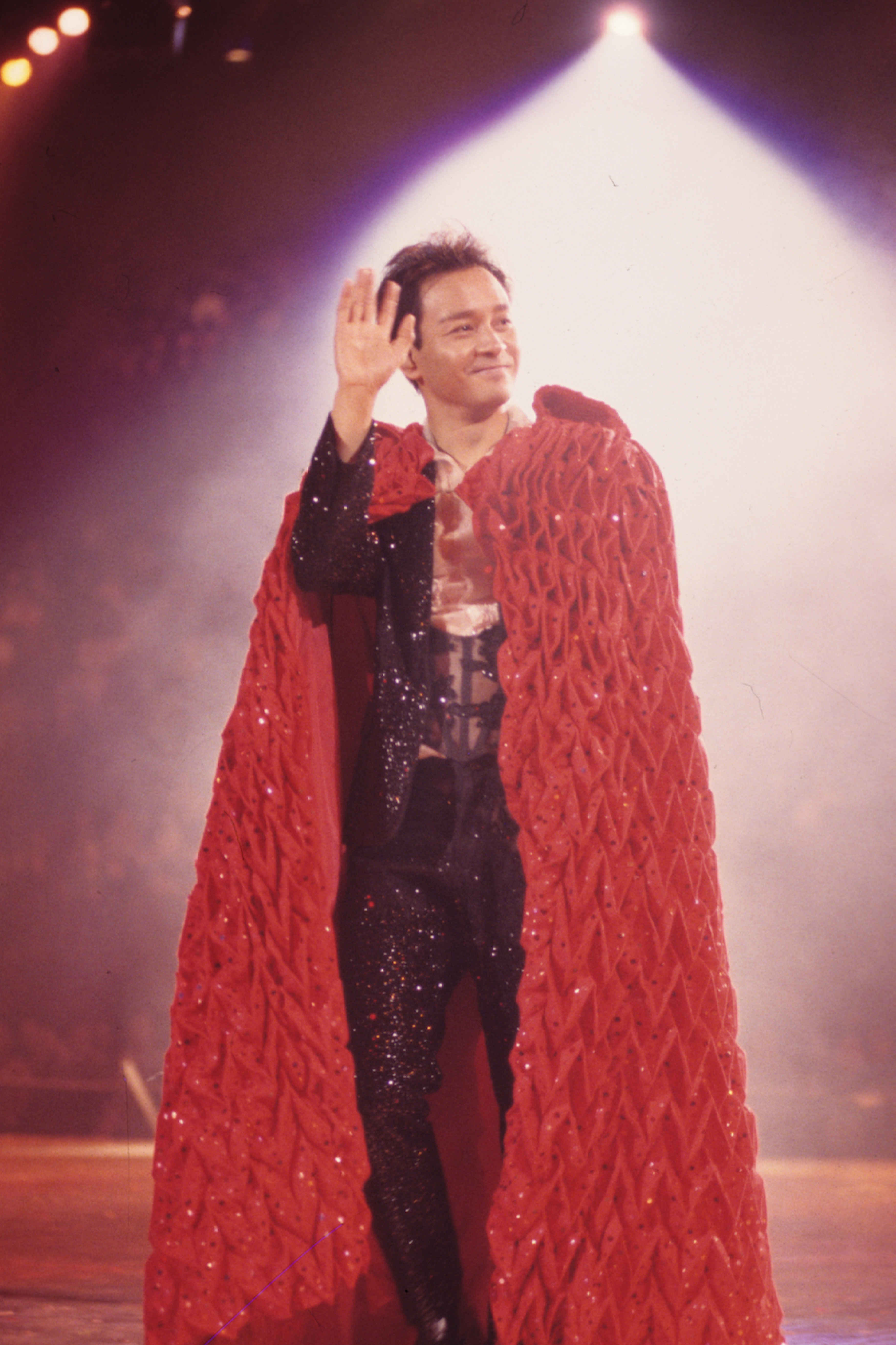 张国荣在《跨越97》演唱会上穿着红色斗篷及闪石西装，表演《红》等多首歌曲。
